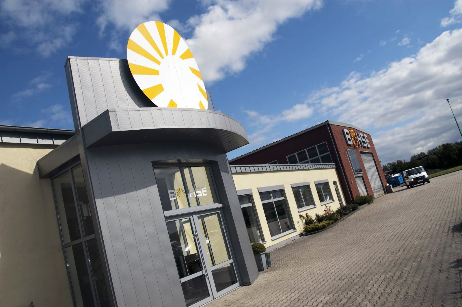Eingang des Firmengebäudes am Wacholderweg 26 in Haren (Ems) mit der großen Bohse-Sonne über der Tür, blauer Himmel