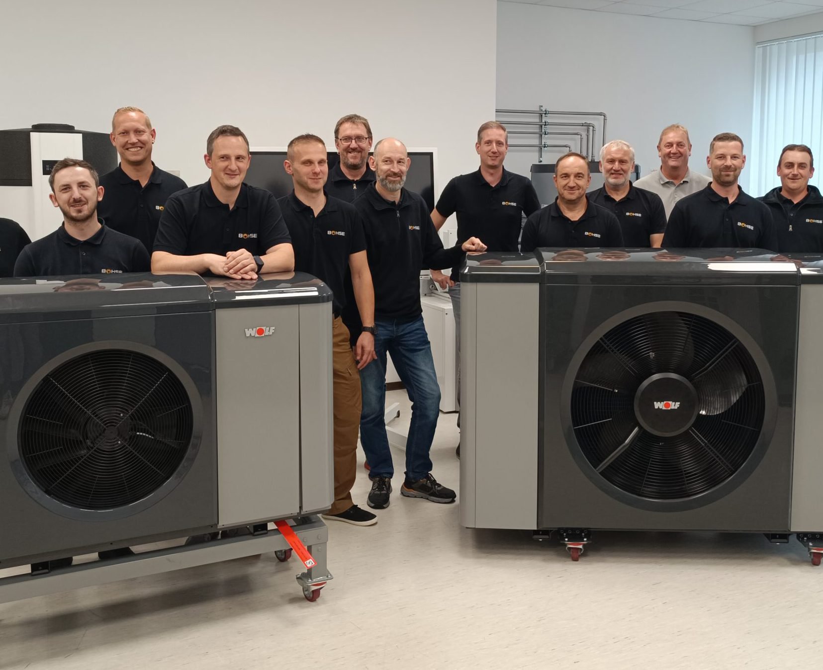 Das Team von Bohse in schwarzen Poloshirts zwischen zwei Wolf-Wärmepumpen